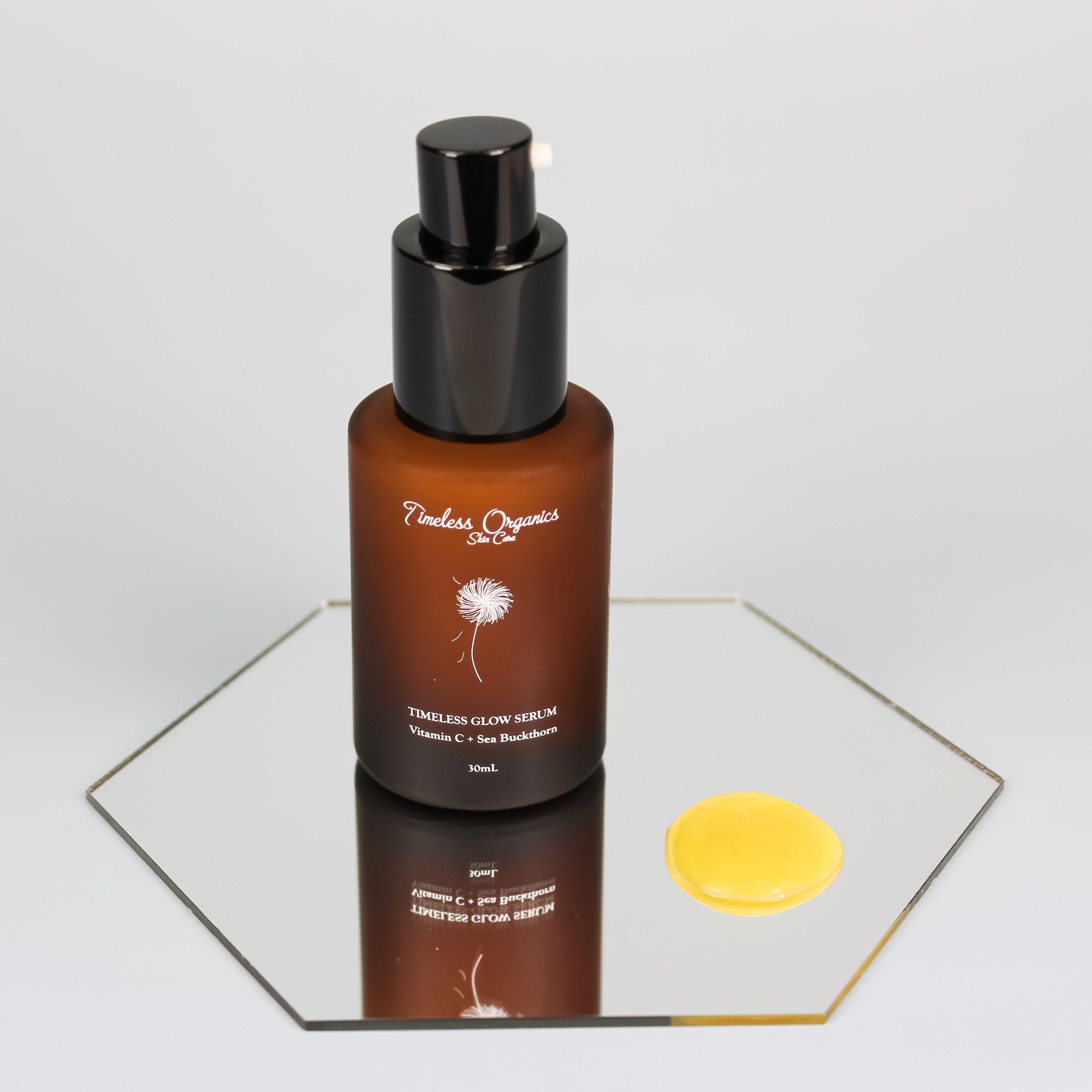Brown serum bottle with black cap on a reflective surface