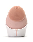 Pink facial cleansing brush with white base on a white background